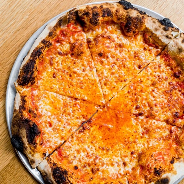 A freshly baked, sliced cheese pizza with a bubbly, charred crust on a metal pan.